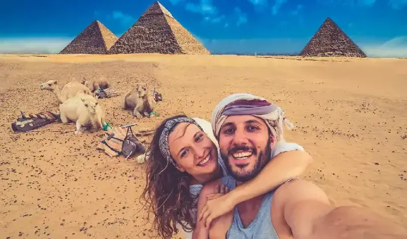 Honeymoon couple taking a photograph beside the Giza Pyramids